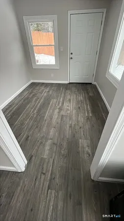 a view of an empty room with wooden floor and a window