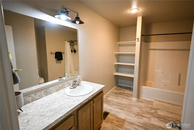 a bathroom with a granite countertop sink mirror and a shower