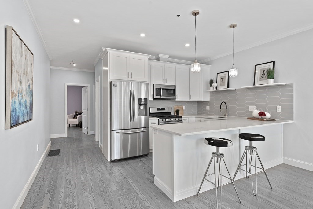 68 Edson Street, Unit 1 Boston, MA 02124 - Photo 4 of 23 a kitchen with stainless steel appliances granite countertop a refrigerator a stove a sink dishwasher and a refrigerator with wooden floor
