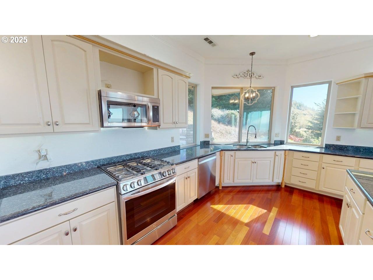 16898 Crown Terrace Brookings, OR 97415 - Photo 8 of 42 a kitchen with stainless steel appliances kitchen island granite countertop a stove a sink and a granite counter tops with white cabinets next to a window