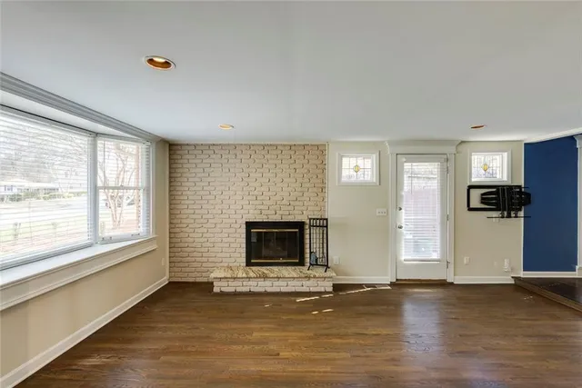 an empty room with windows fireplace and wooden floor
