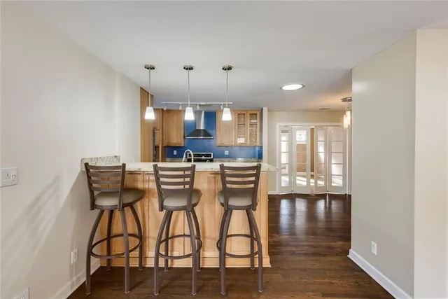 a kitchen with stainless steel appliances kitchen island granite countertop a dining table chairs and a refrigerator