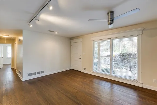 an empty room with wooden floor and windows