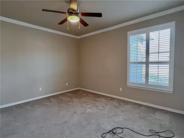 a view of an empty room with chandelier fan and a window