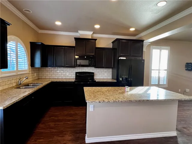 a kitchen with kitchen island granite countertop a sink stove and refrigerator
