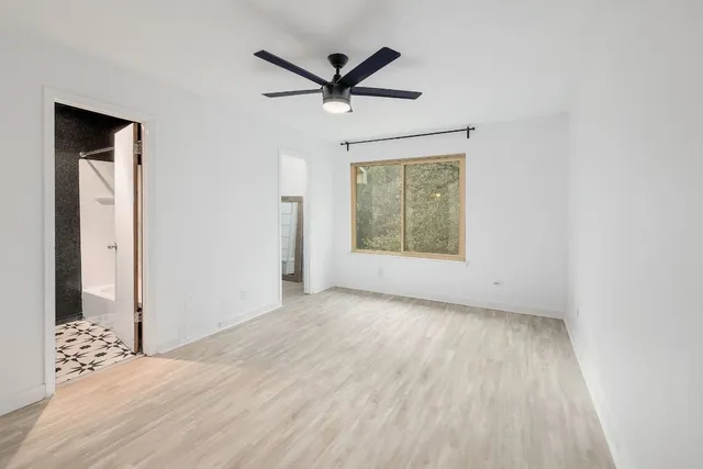an empty room with ceiling fan and window