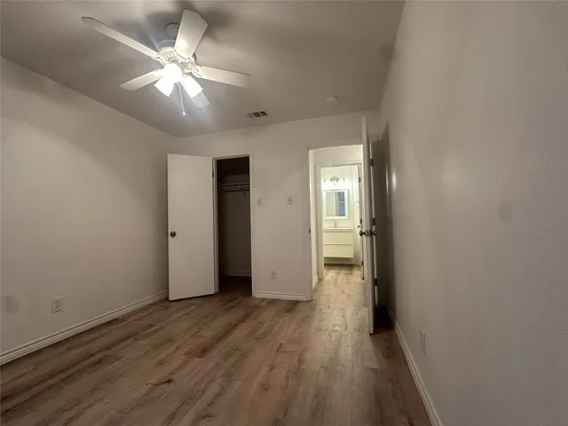 an empty room with wooden floor and a ceiling fan
