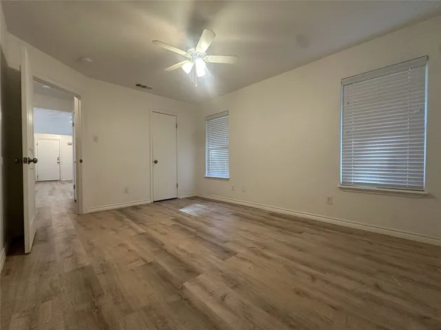 an empty room with wooden floor and windows