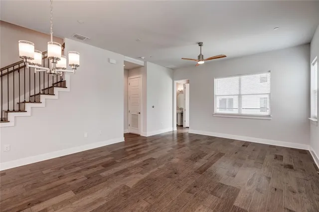 an empty room with wooden floor chandelier and windows