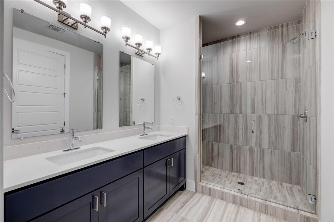 4600 Freedom Drive Austin, TX 78731 - Photo 23 of 40 a bathroom with a double vanity sink a large mirror and shower