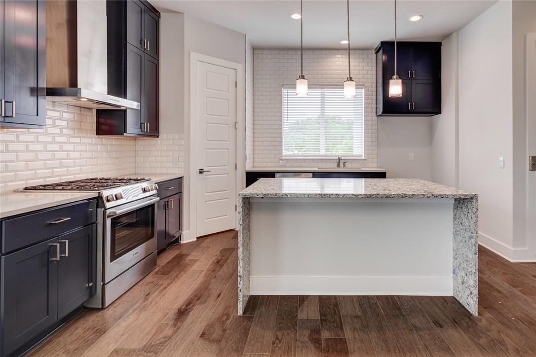 4600 Freedom Drive Austin, TX 78731 - Photo 4 of 40 a kitchen with granite countertop a stove a sink and a microwave