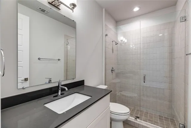 a bathroom with a granite countertop sink toilet a mirror a vanity and shower