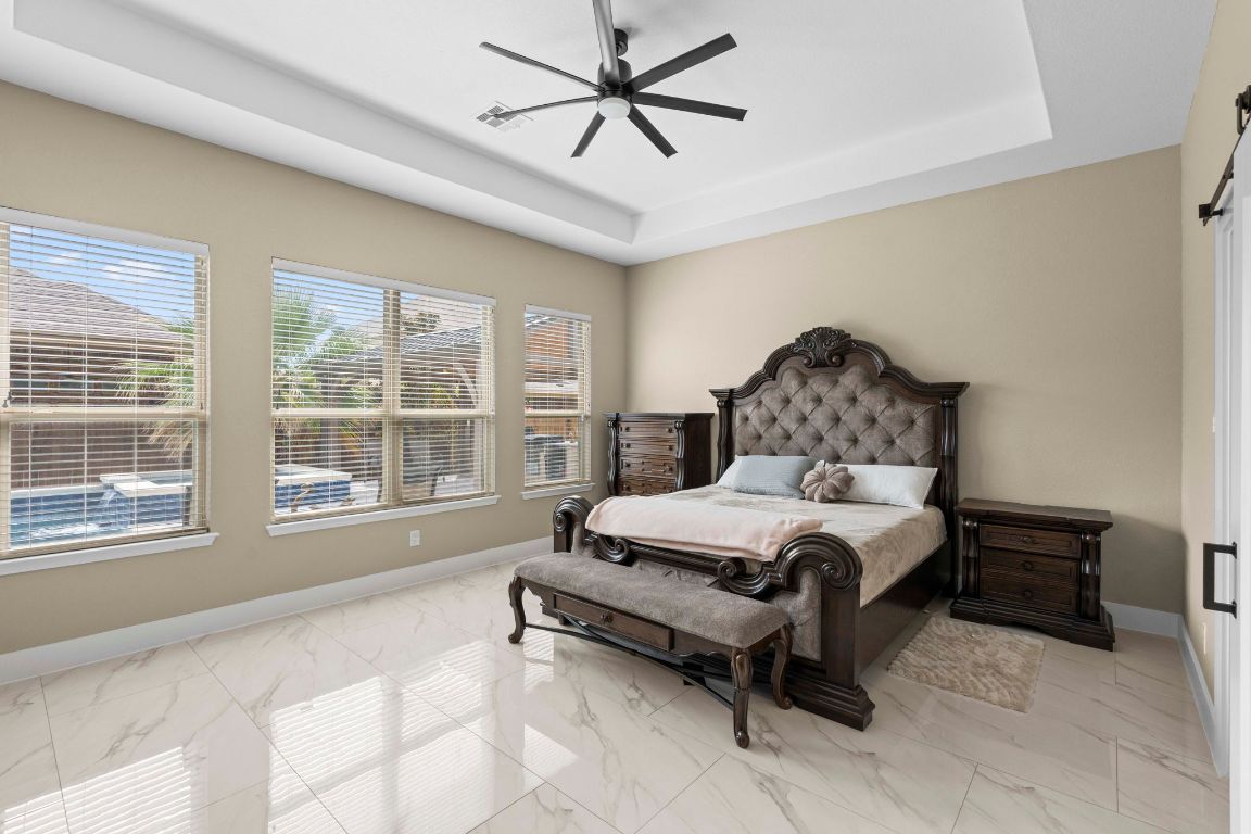 3301 Falconers Way Pflugerville, TX 78660 - Photo 23 of 39 Bedroom featuring a tray ceiling, light marble finish floors, and ceiling fan