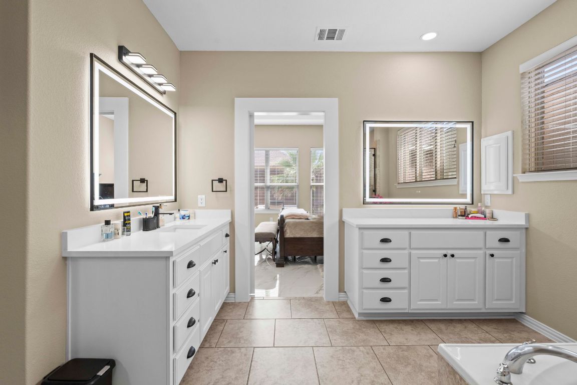 3301 Falconers Way Pflugerville, TX 78660 - Photo 28 of 39 Ensuite bathroom with two vanities, light tile patterned floors, and tiled tub