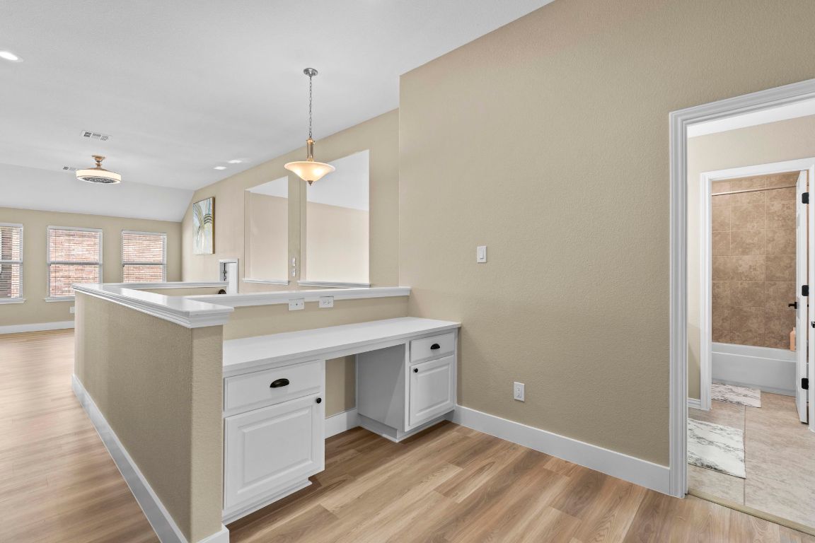 3301 Falconers Way Pflugerville, TX 78660 - Photo 32 of 39 Kitchen featuring white cabinetry, pendant lighting, light countertops, light wood finished floors, and a peninsula