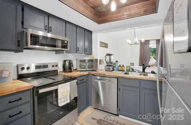 a kitchen with stainless steel appliances granite countertop a sink a stove a microwave and wooden cabinets