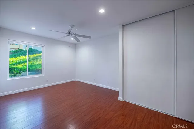an empty room with wooden floor chandelier fan and windows