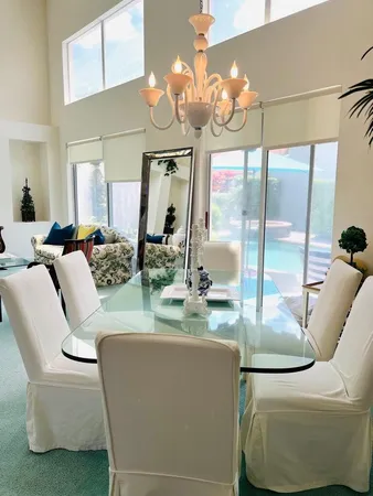 a dining room with couches a chandelier and kitchen view