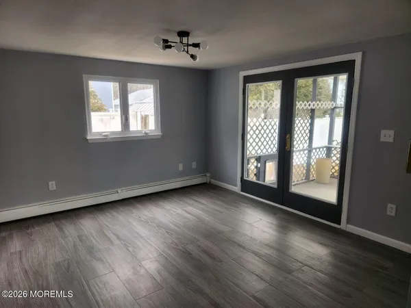 a view of an empty room with wooden floor and a window