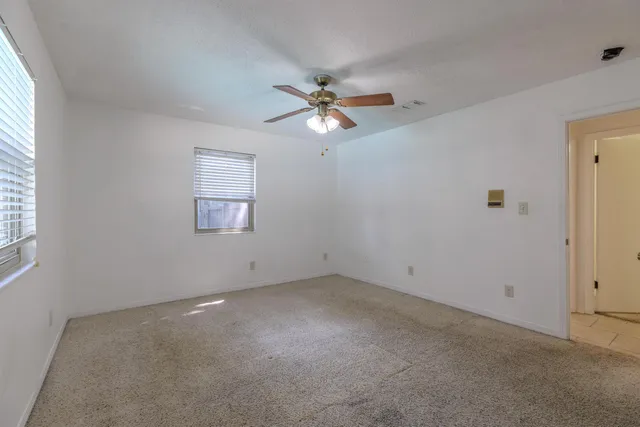 an empty room with windows and fan