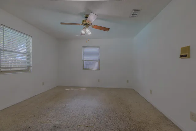 an empty room with a window and a fan