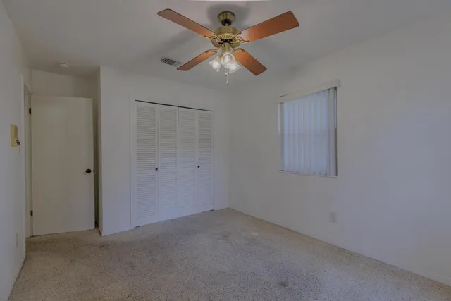an empty room with a window and a fan