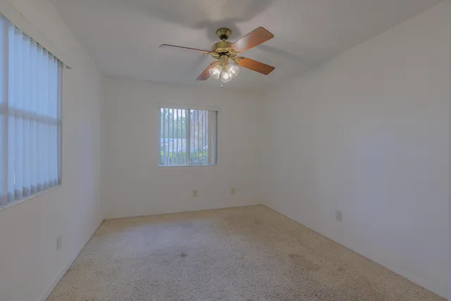 an empty room with chandelier fan and windows