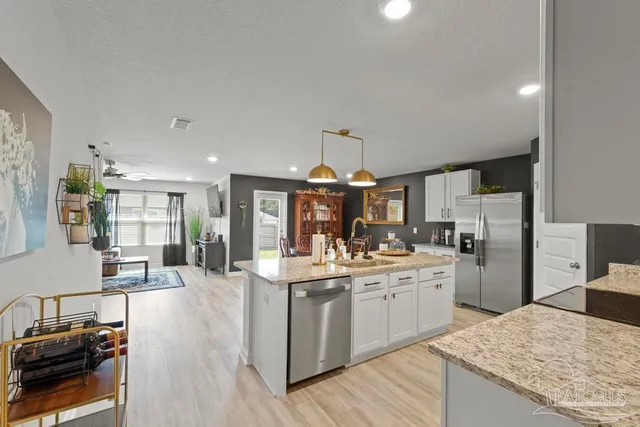 a kitchen with stainless steel appliances kitchen island granite countertop a sink stove and refrigerator