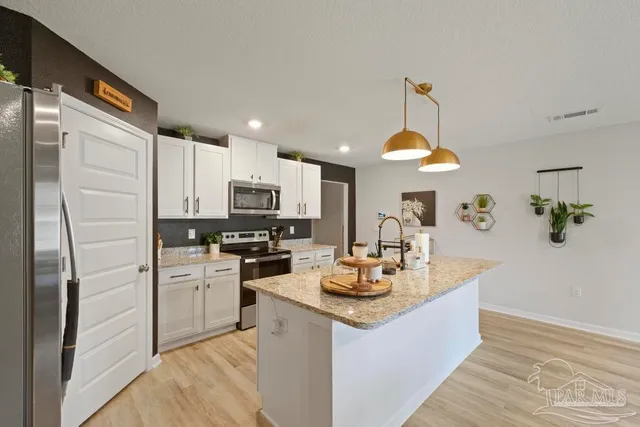 a kitchen with a refrigerator a stove a sink dishwasher a dining table and chairs with wooden floor