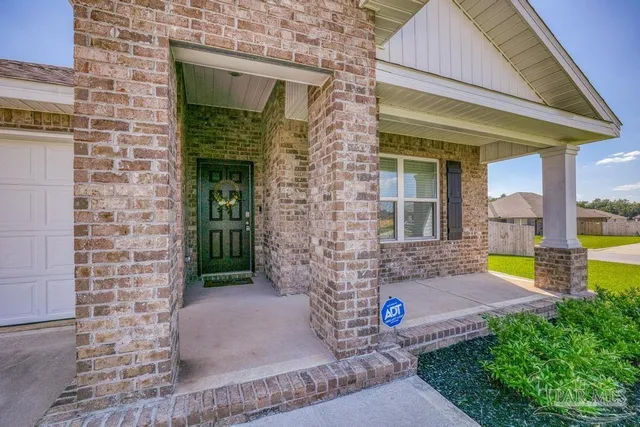 a view of a brick house with a yard potted plants