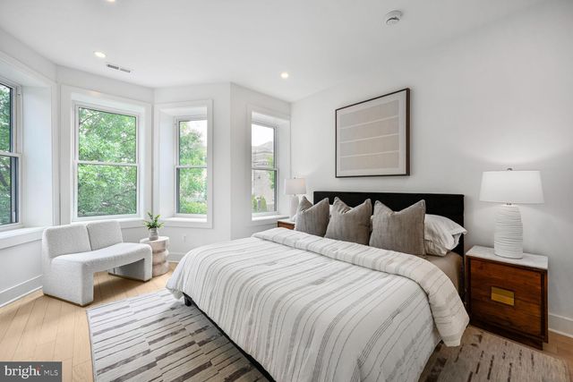 a bedroom with a bed and a lamp on dresser