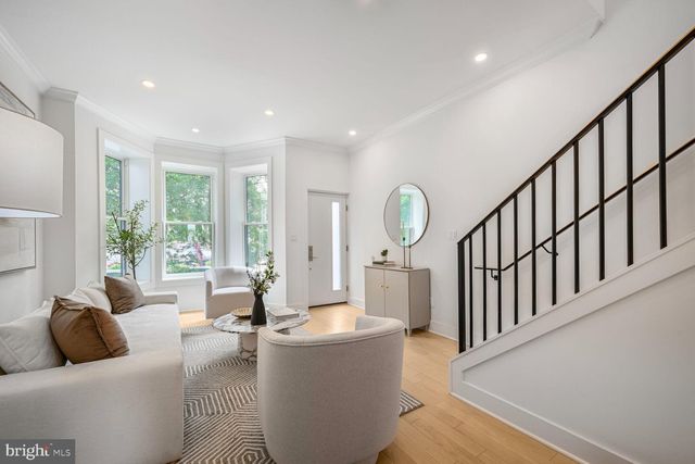 a kitchen with stainless steel appliances a refrigerator a sink a stove and white cabinets with wooden floor