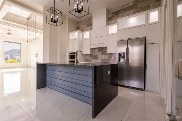 a kitchen with stainless steel appliances kitchen island granite countertop a refrigerator and a sink