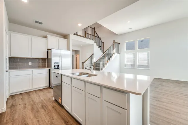 a kitchen with white cabinets and wooden floor
