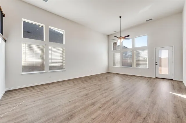 a view of empty room with wooden floor and fan