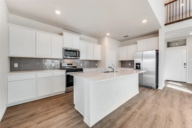 a kitchen with white cabinets and stainless steel appliances