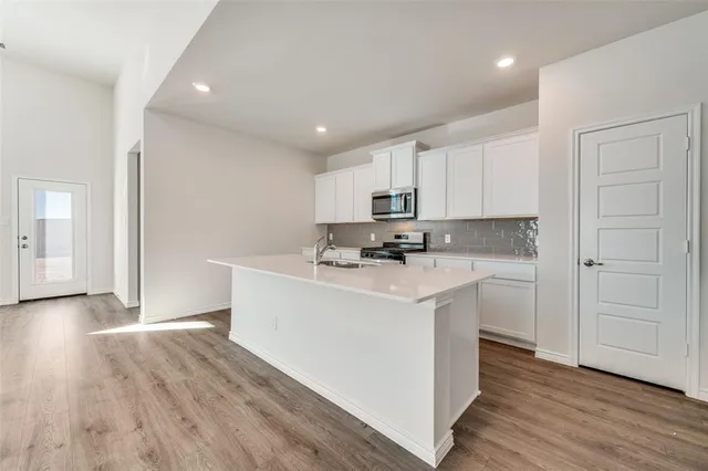 a kitchen with wooden floors a sink a counter top space and cabinets