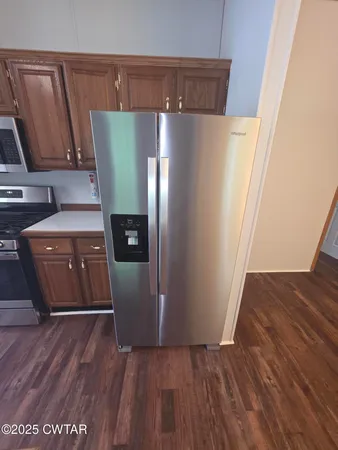 a kitchen with stainless steel appliances a stove a refrigerator a sink a oven with wooden floor
