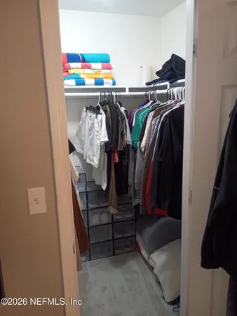 a view of walk in closet with clothes and shoes