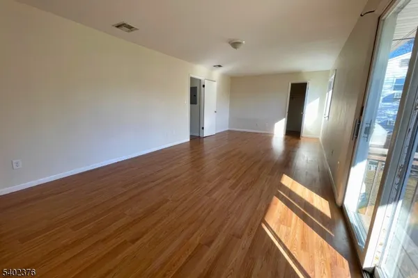 a view of an empty room with wooden floor and a window