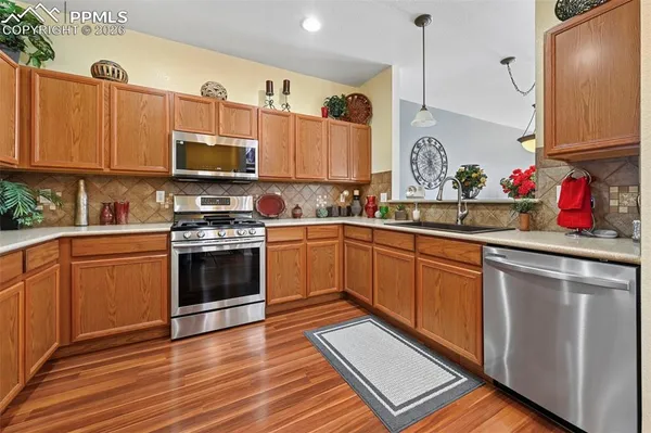 a kitchen with stainless steel appliances a sink dishwasher a stove top oven a refrigerator with cabinets and wooden floor