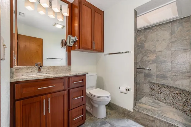 a bathroom with a granite countertop toilet sink and mirror