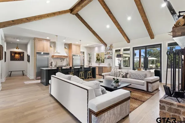 a living room with stainless steel appliances kitchen island granite countertop a large counter top and couches with wooden floor