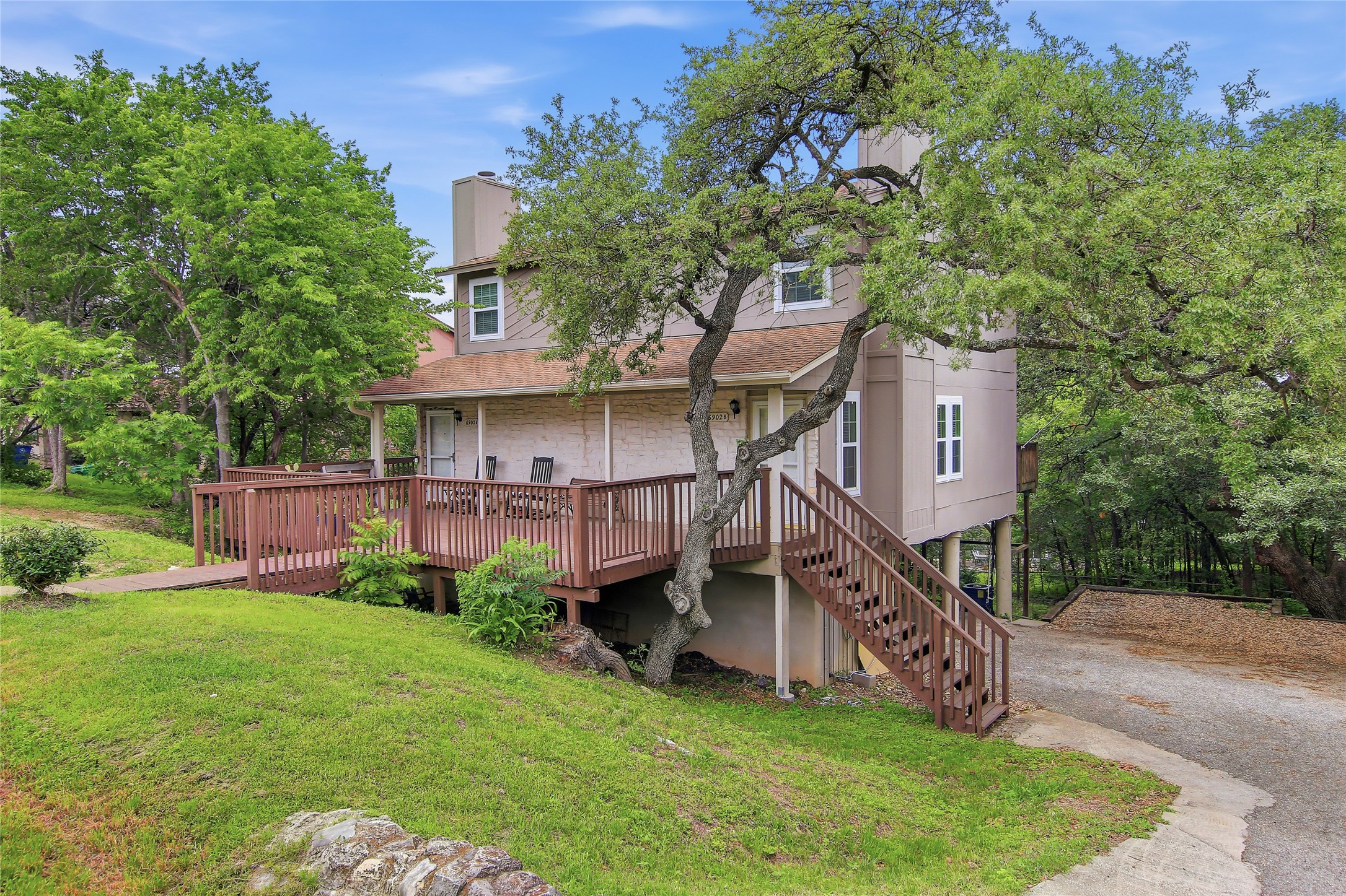 6902 Rifle Bend, Unit B Austin, TX 78736 - Photo 22 of 34 a view of a house with a big yard potted plants and a large tree
