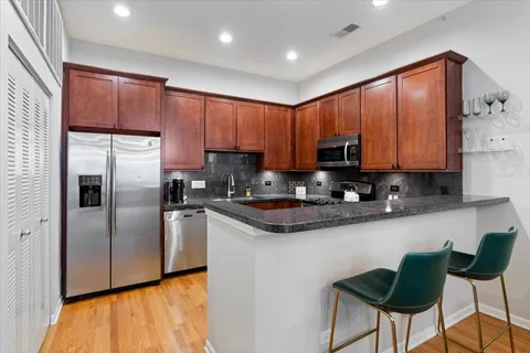 a kitchen with stainless steel appliances granite countertop a refrigerator a stove a sink and a microwave