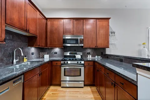 a kitchen with granite countertop wooden cabinets and a stove top oven