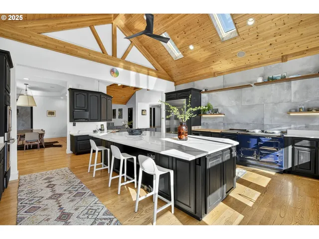 a kitchen with stainless steel appliances granite countertop a stove a sink dishwasher and a dining table with the view of living room