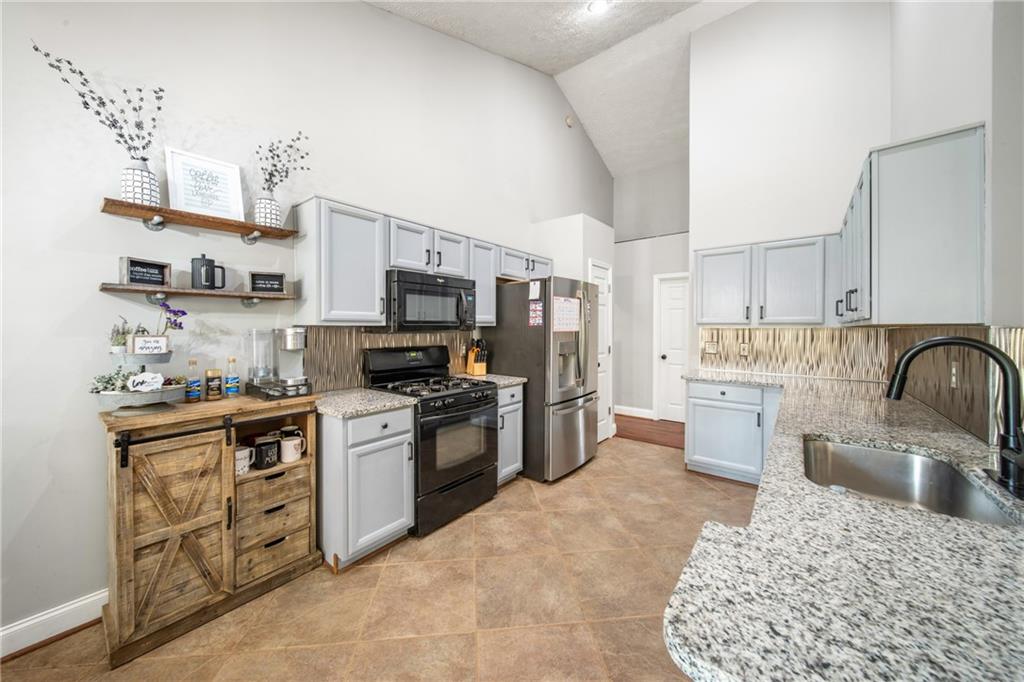 174 Foxtail Pass Acworth, GA 30101 - Photo 14 of 38 a kitchen with stainless steel appliances granite countertop a sink dishwasher stove refrigerator and cabinets