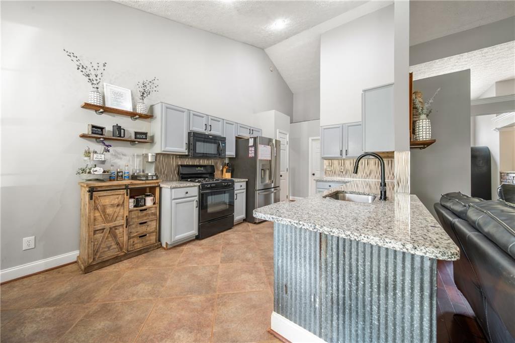 174 Foxtail Pass Acworth, GA 30101 - Photo 15 of 38 a kitchen with stainless steel appliances kitchen island granite countertop a sink stove and refrigerator