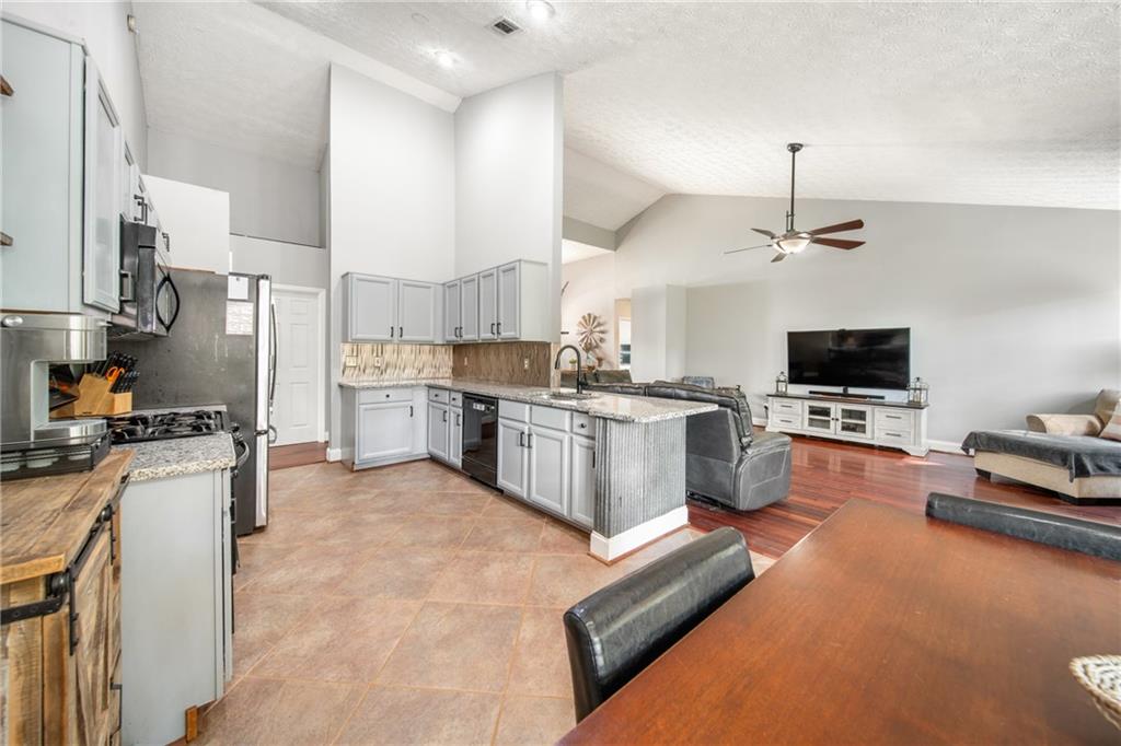 174 Foxtail Pass Acworth, GA 30101 - Photo 18 of 38 a kitchen with stainless steel appliances granite countertop a stove top oven a sink dishwasher a dining table and chairs with wooden floor